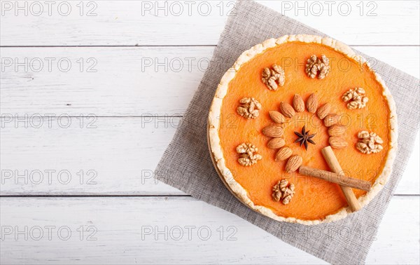 Traditional american sweet pumpkin pie decorated with nuts, on white wooden background. top view,