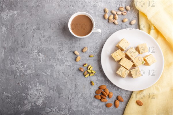 Traditional indian candy soan papdi in white plate with almond, pistache and a cup of coffee on a