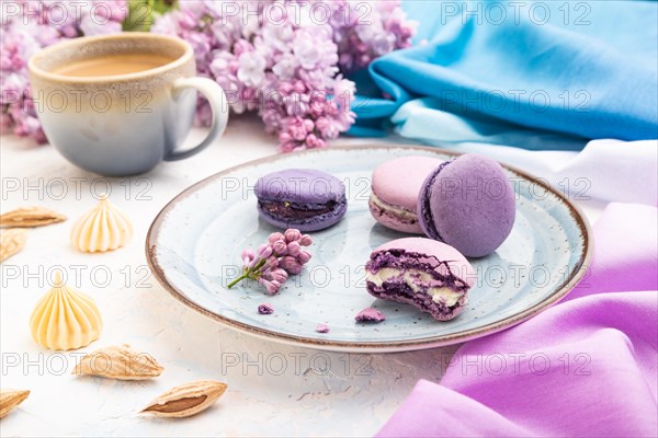 Purple macarons or macaroons cakes with cup of coffee on a white concrete background and