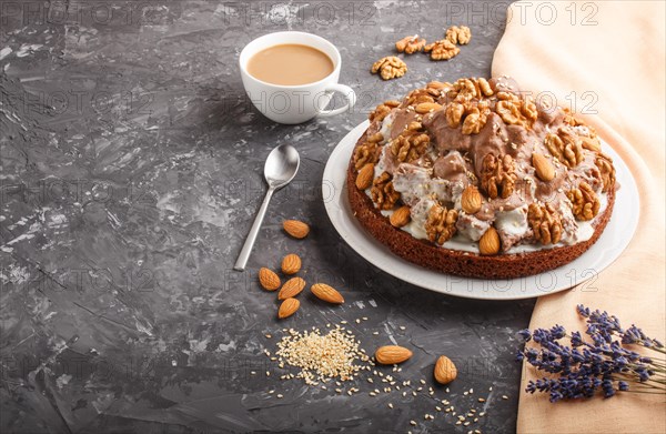 Homemade cake with milk cream, cocoa, almond, hazelnut on a black concrete background with orange