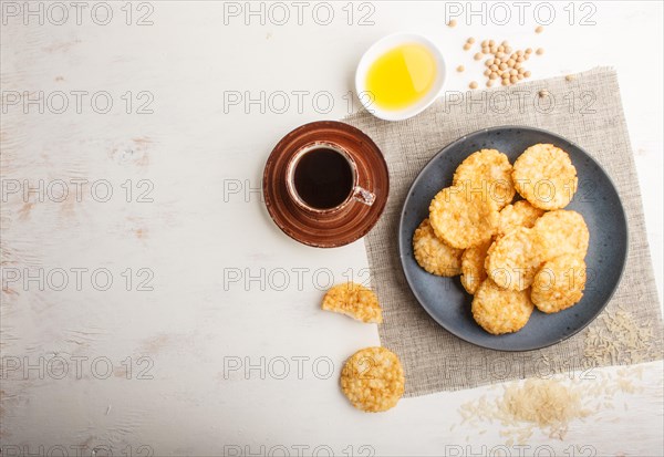 Traditional japanese rice chips cookies with honey and soy sauce on a blue ceramic plate and a cup