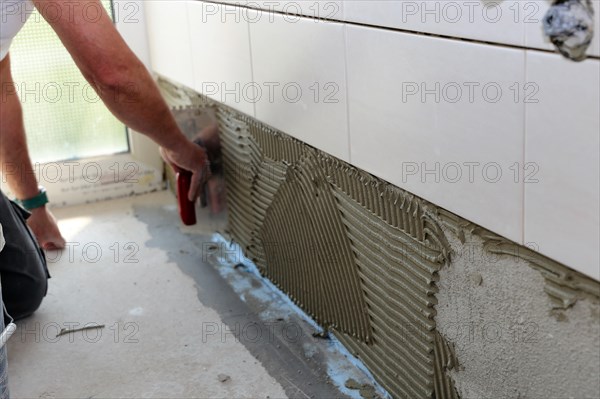 Tiler lays tiles on the wall