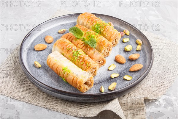 Baklava, traditional arabic sweets in gray ceramic plate on a gray concrete background. side view,