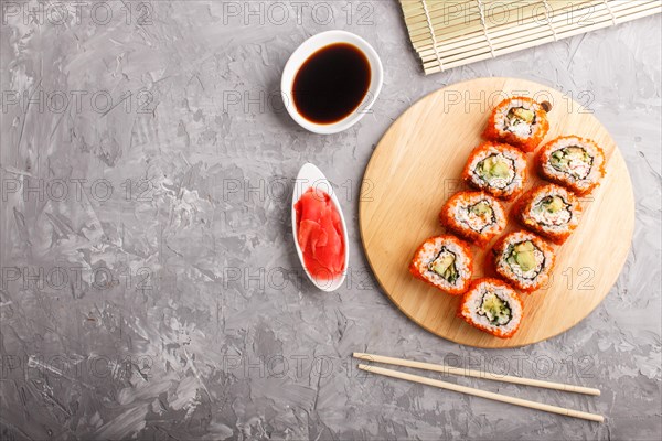 Japanese maki sushi rolls with flying fish roe, chopsticks, soy sauce and marinated ginger on