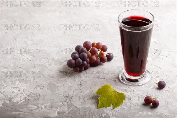 Glass of red grape juice on a gray concrete background. Morninig, spring, healthy drink concept.