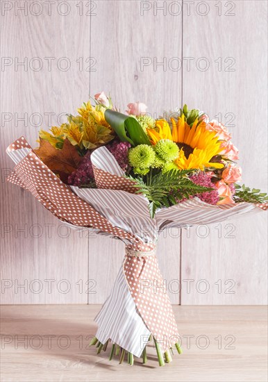 Bouquet of alstroemeria, sunflower, roses, chrysanthemum on a wooden background. floristic