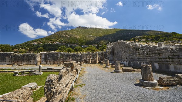 Ruins of an ancient site with broken columns and stones under a blue sky, Sanctuary of Asclepius,