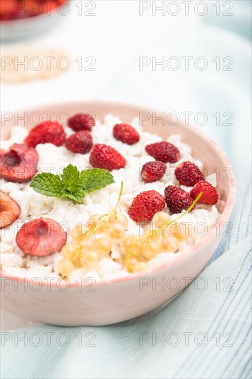 Rice flakes porridge with milk and strawberry in ceramic bowl on white concrete background and blue