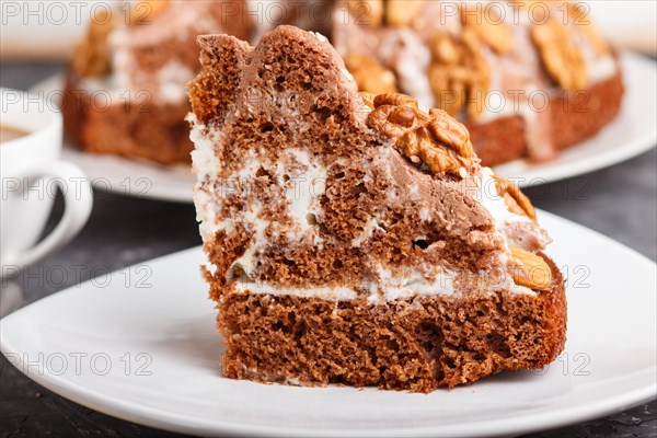 Homemade cake with milk cream, cocoa, almond, hazelnut on a black concrete background and a cup of