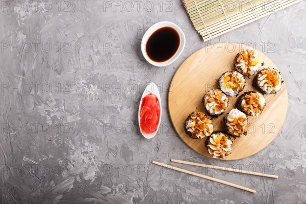 Japanese maki sushi rolls with cream cheese, chopsticks, soy sauce and marinated ginger on wooden