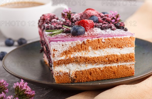 Berry cake with milk cream and blueberry jam on blue ceramic plate with cup of coffee and fresh