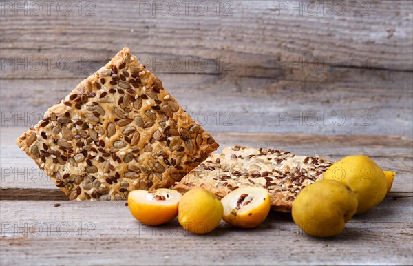 Biscuits with flax, sesame and sunflower seeds and yellow quince fruit on a rustic wooden