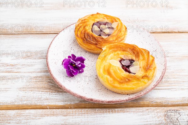 Small cheesecakes with jam and almonds on a white wooden background. Side view, close up