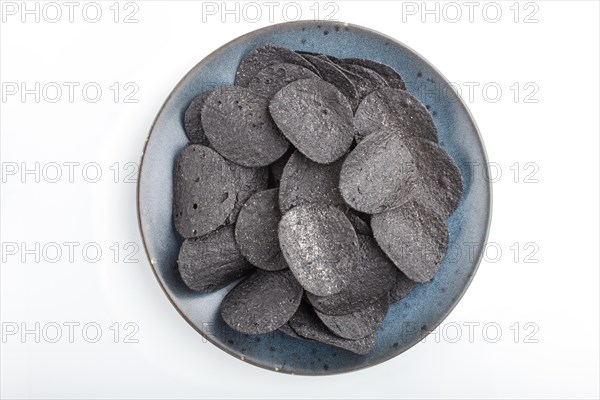 Black potato chips with charcoal on a blue ceramic plate isolated on white background. Top view,