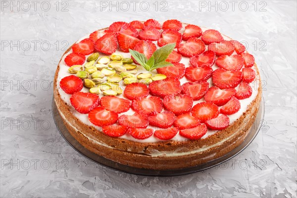 Homemade cake with yoghurt cream, strawberry and pistachio on a gray concrete background. side