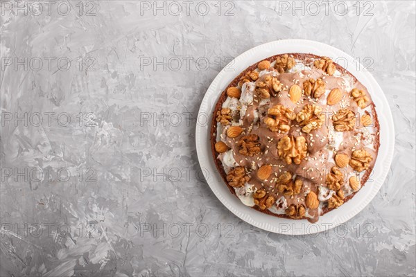 Homemade cake with milk cream, cocoa, almond, hazelnut on a gray concrete background with orange