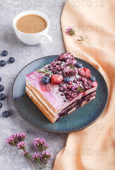 Berry cake with milk cream and blueberry jam on blue ceramic plate with cup of coffee and fresh