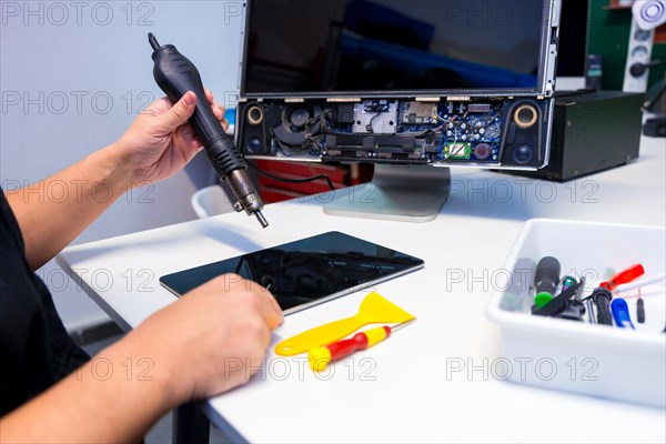 Side view of an unrecognizable technician fixing a computer component using a soldering iron in a