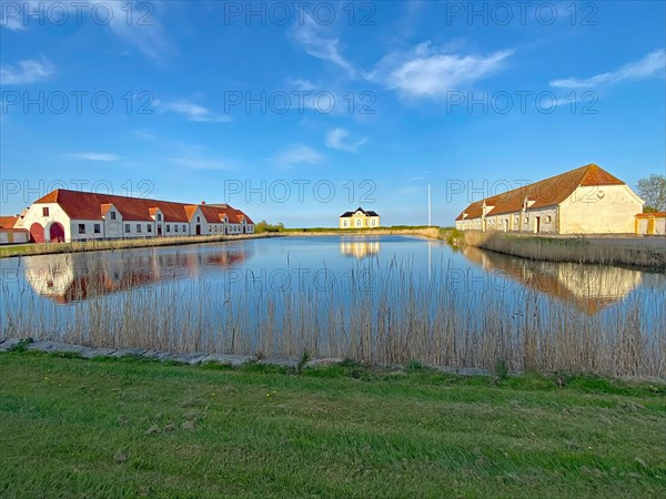Large houses and the teahouse at Valdemars Slot are reflected in the calm water, Valdemars Slot,