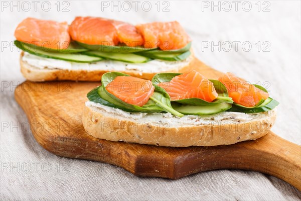 Smoked salmon sandwiches with cucumber and spinach on wooden board on a linen background. side