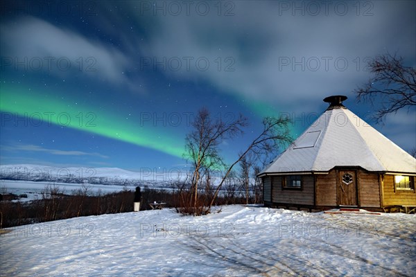 Northern Lights (aurora boreailis) over a small wooden hut in Swedish Lapland, Abisko, Kiruna,