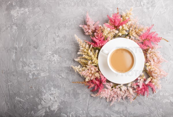 Pink and red astilbe flowers and a cup of coffee on a gray concrete background. Morninig, spring,