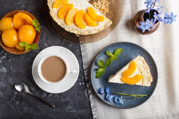 A piece of peach cheesecake on a blue ceramic plate with blue flowers and a cup of coffee on a