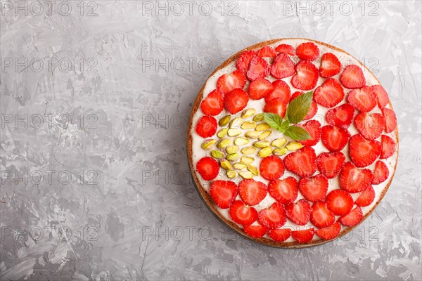 Homemade cake with yoghurt cream, strawberry and pistachio on a gray concrete background. top view.