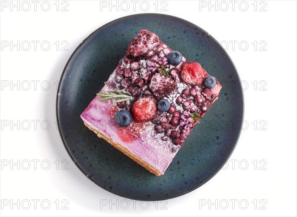 Berry cake with milk cream and blueberry jam on blue ceramic plate isolated on white background.