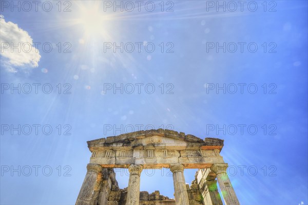 Sunshine pierces the ruins of an ancient temple with columns against a blue sky, Mausoleum, Heroon,