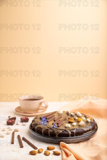 Homemade chocolate brownie cake with caramel cream and almonds with cup of coffee on a white and