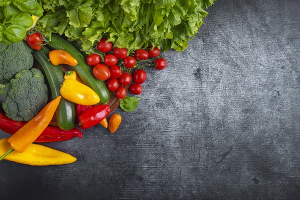 Fresh lettuce, courgettes, broccoli, tomatoes and peppers arranged on a wooden board symbolises