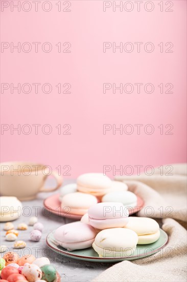 Colored zephyr or marshmallow with cup of coffee and dragees on a gray and pink background and