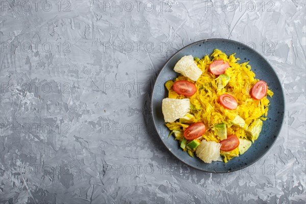 Fried pomelo with tomatoes and avocado on gray concrete background. Top view, copy space, myanmar