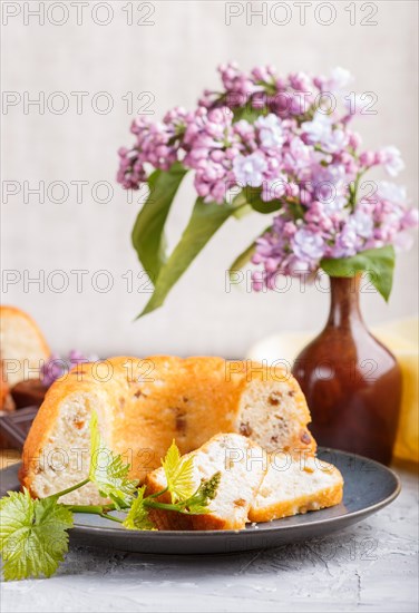 Cakes with raisins and chocolate and a cup of coffee. lilac flowers on a gray concrete background,