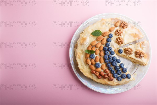 Homemade layered Napoleon cake with milk cream. Decorated with blueberry, almonds, walnuts,