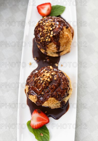 Fresh profiteroles with ice cream and chocolate on a white plate. selective focus. horizontal. top
