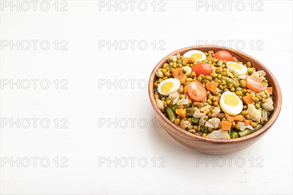 Mung bean porridge with quail eggs, tomatoes and microgreen sprouts on a white wooden background.