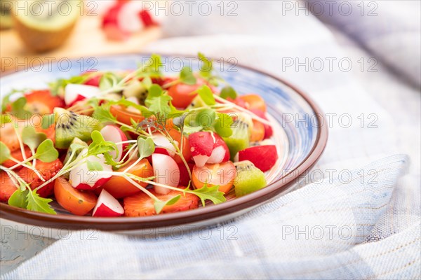 Vegetarian fruits and vegetables salad of strawberry, kiwi, tomatoes, microgreen sprouts on white