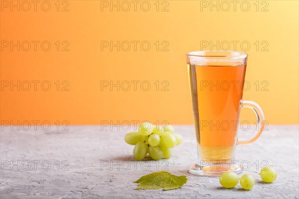 Glass of green grape juice on a gray and orange background. Morninig, spring, healthy drink concept
