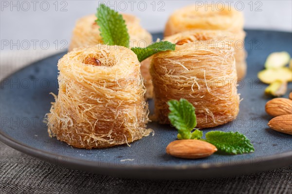 Kunafa, traditional arabic sweets in blue ceramic plate on a gray concrete background. side view,