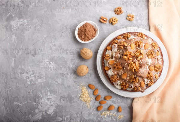 Homemade cake with milk cream, cocoa, almond, hazelnut on a gray concrete background with orange