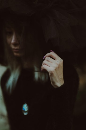 Close-up image with a woman's face partially obscured by tulle fabric, creating an enigmatic feel