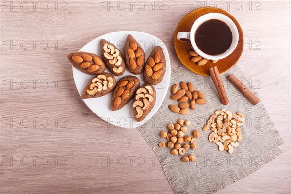 Small cakes potatoes with almonds and cashew nuts on a dessert plate. A cup of coffee, cinnamon,