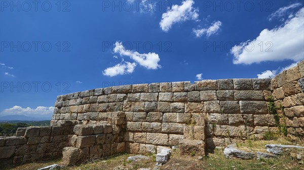 An ancient wall of stones under a blue sky with fluffy clouds, Ancient city wall, Archaeological