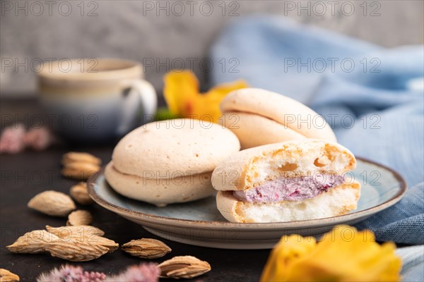 Meringues cakes with cup of coffee on a black concrete background and blue linen textile. Side