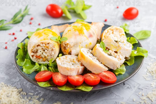 Stuffed baked squid with greens on a blue ceramic plate on a gray concrete background, side view,