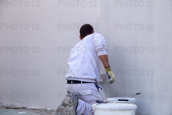 Plasterers plaster the facade of a new building (Mutterstadt development area,