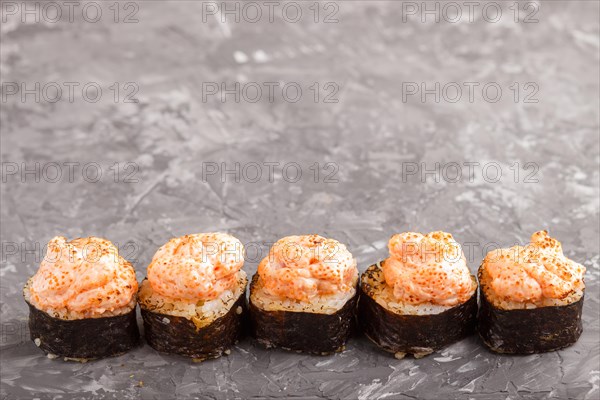 Japanese maki sushi rolls with flying fish roe, cheese on black concrete background. Side view,