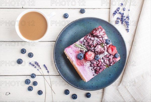 Berry cake with milk cream and blueberry jam on blue ceramic plate with cup of coffee and fresh